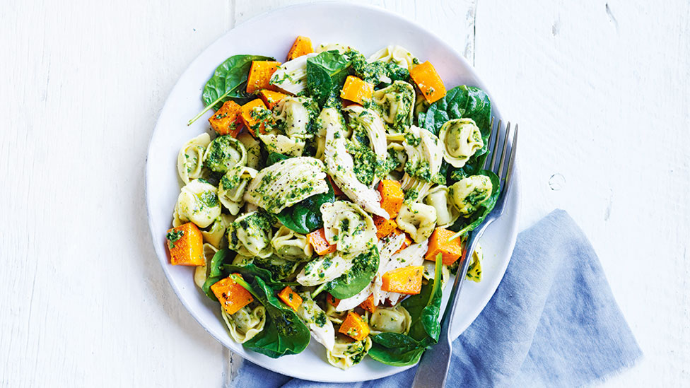 Chicken, pumpkin, spinach and pesto pasta served in a bowl with a fork beside the bowl