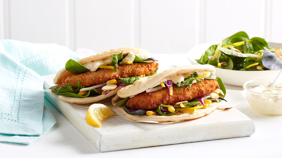 Crumbed fish, shreaded vegetables and corn in flat bread with slice of lemon, tartare sauce and salad on the side