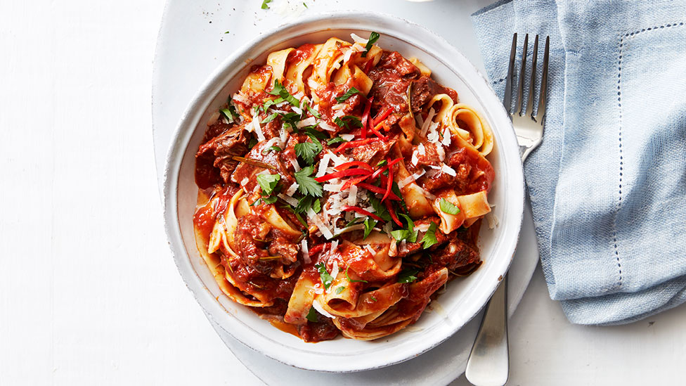 Lamb ragu served in a bowl with coriander and red pepper garnish