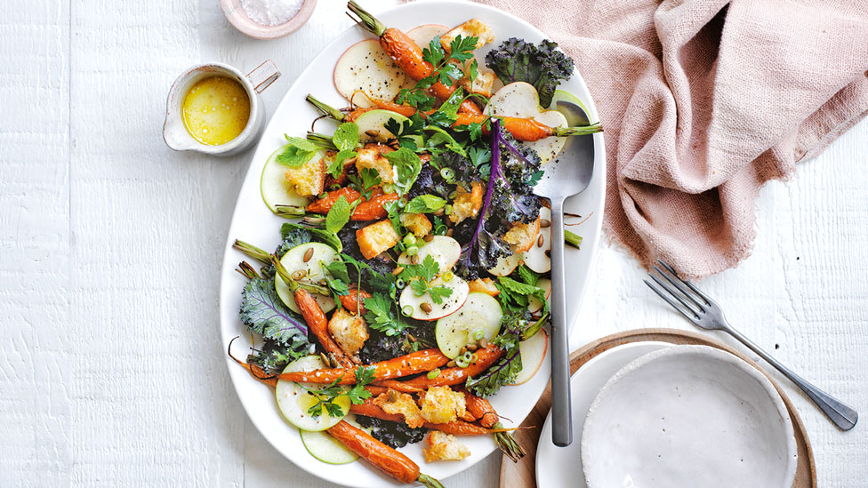 Roasted carrots, radish, pear, kale and herbs served on a plate