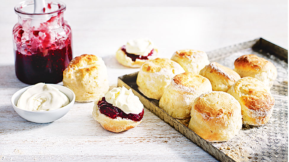 Scones on Baking Tray, one cut in half with Jam and Cream
