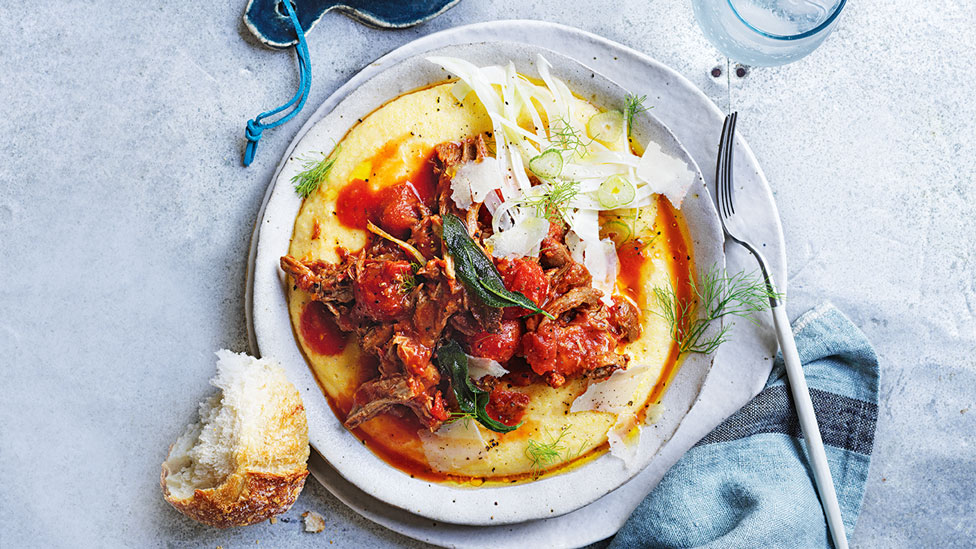 Pork ragu served on top of polenta with fennel and fried sage on top with bread on the side