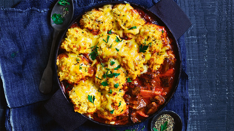 Slow cooker beef with cheesy dumplings on top served in a baking dish