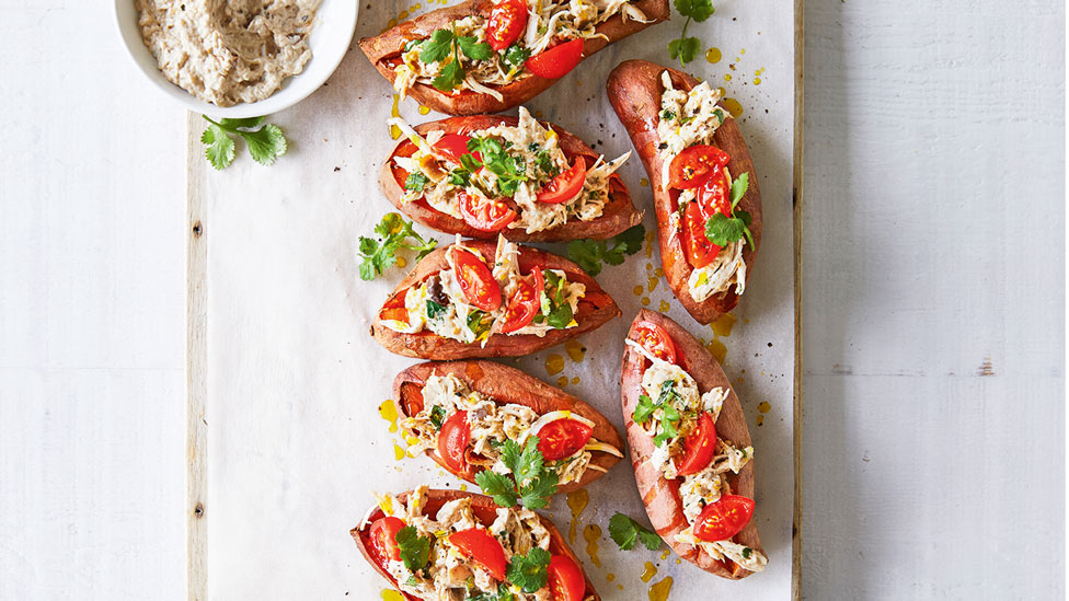 Seven sweet potatoes stuffed with chicken and tomatoes with a coriander garnish and baba ganoush on the side