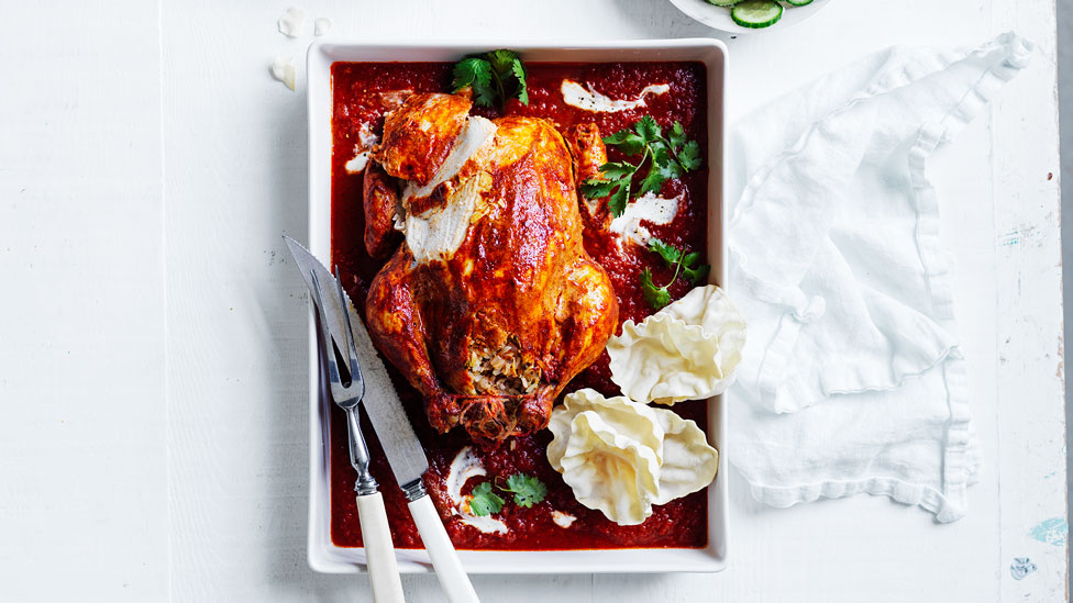 Roast tandoori-style chicken in a baking dish served with tandoori sauce, coriander and pappadums