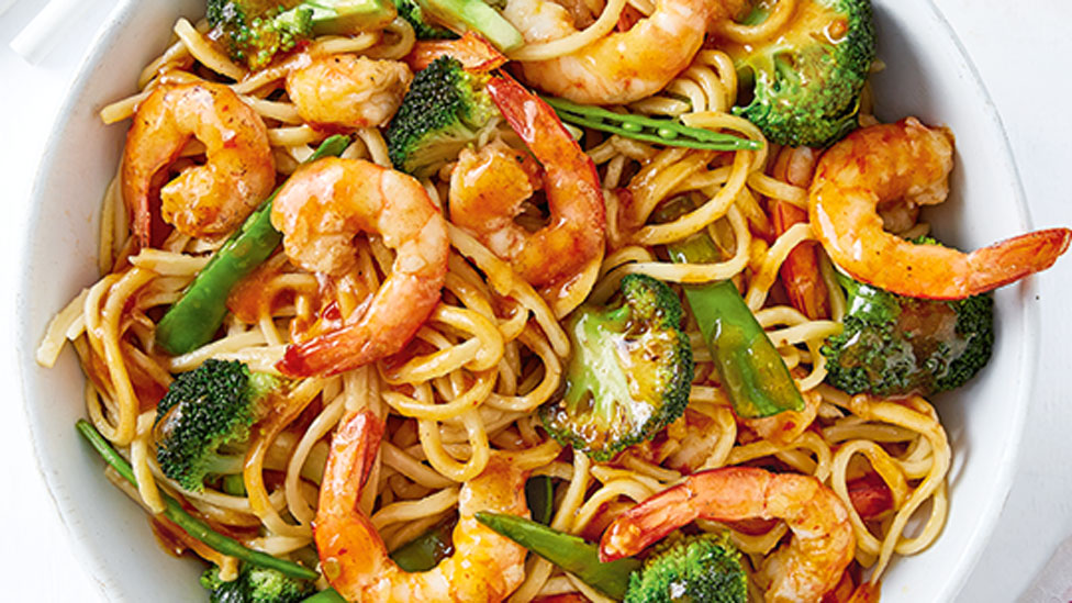 Prawns and noodles tossed with broccoli and snow peas served in a bowl