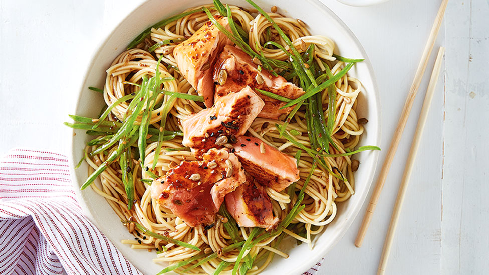 Salmon served on top of ramen noodles in a bowl with chopsticks