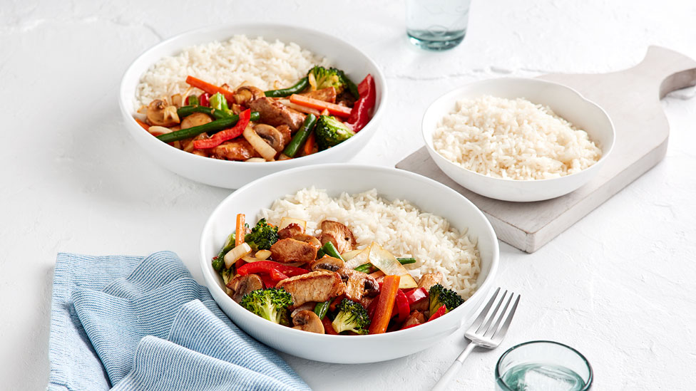 Asian-style Pork Stir-Fry in two bowls with rice, with a side bowl of rice