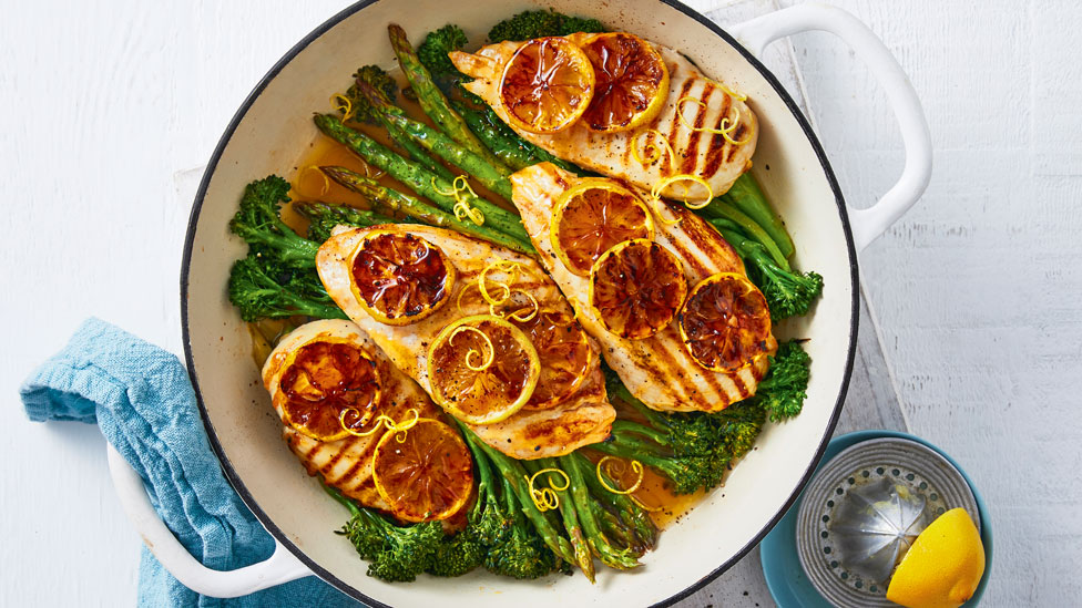 Baked Lemon Chicken with Spring Greens in roasting dish, with baked lemon slices and lemon zest