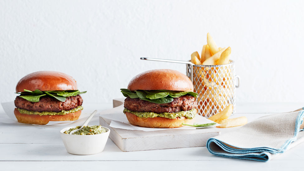 Beef and Thyme Burgers on a chopping board, with a side of chips and extra dip in a bowl