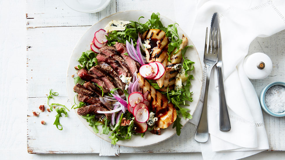 Beef, Blue Cheese and Pear Salad on a plate next to cutlery