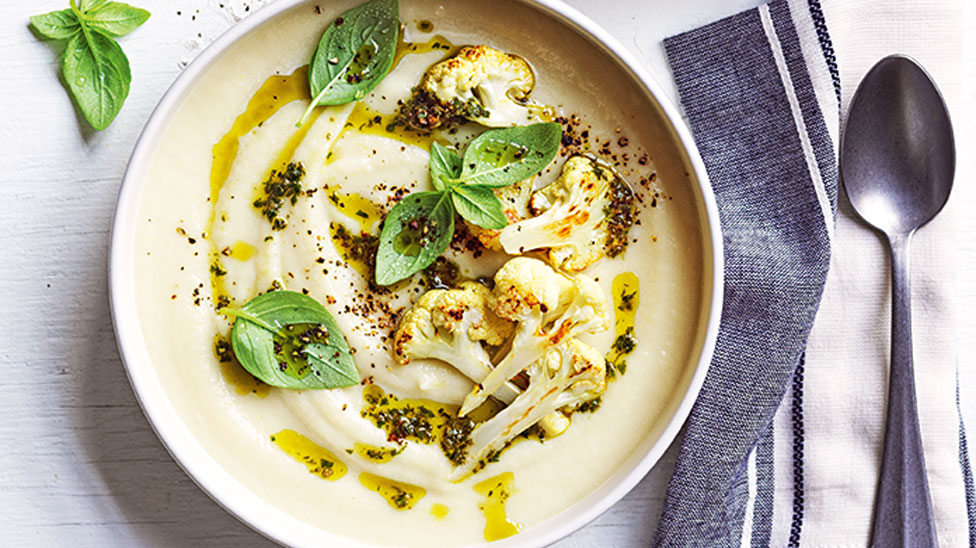 Cauliflower soup served n a bowl with smoked almond pesto on top