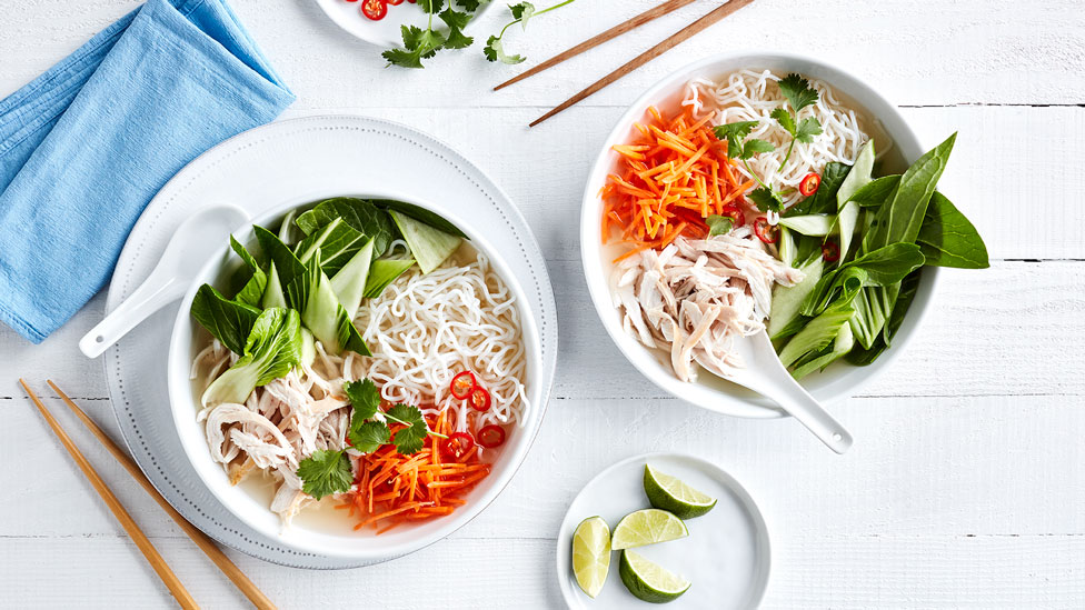 Easy Chicken Pho in two serving bowls with lime wedges to serve