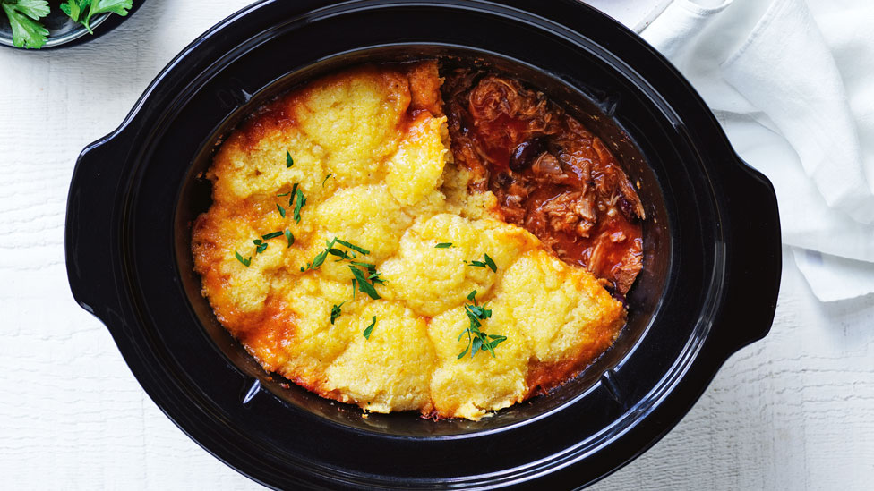 Chilli Pork with Polenta Dumplings in serving dish, topped with flat leaf parsley