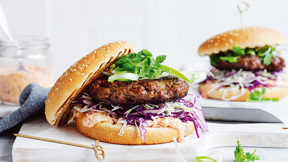 Open style Korean Burgers with Kimchi Mayo on a wooden board. Topped with Coriander