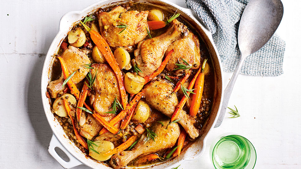 French-style Mustard and White Wine Chicken in pot, next to spoon on cloth and a glass