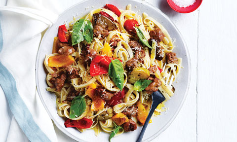 Italian-style Sausage Pasta in a bowl, sprinkled with basil leaves and Parmesan