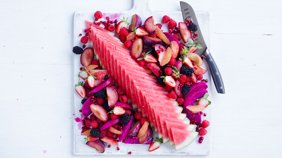 Pink fruit platter on a white chopping board