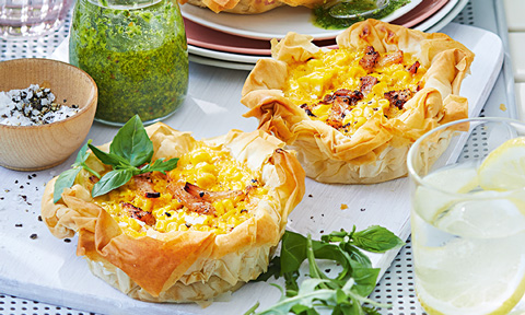Two bacon and corn quiches with pesto, oil and salad