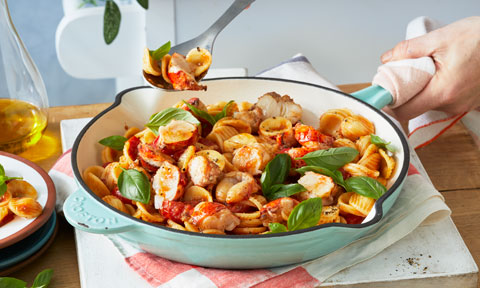 A pan of orecchiette pasta with lobster, tomato, shallot and fresh basil.