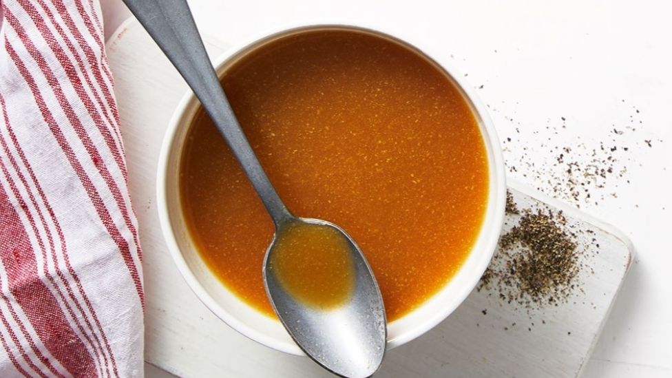 Luke Mangan’s honey-mustard ham glaze in a bowl, with a serving spoon and spices on the side.