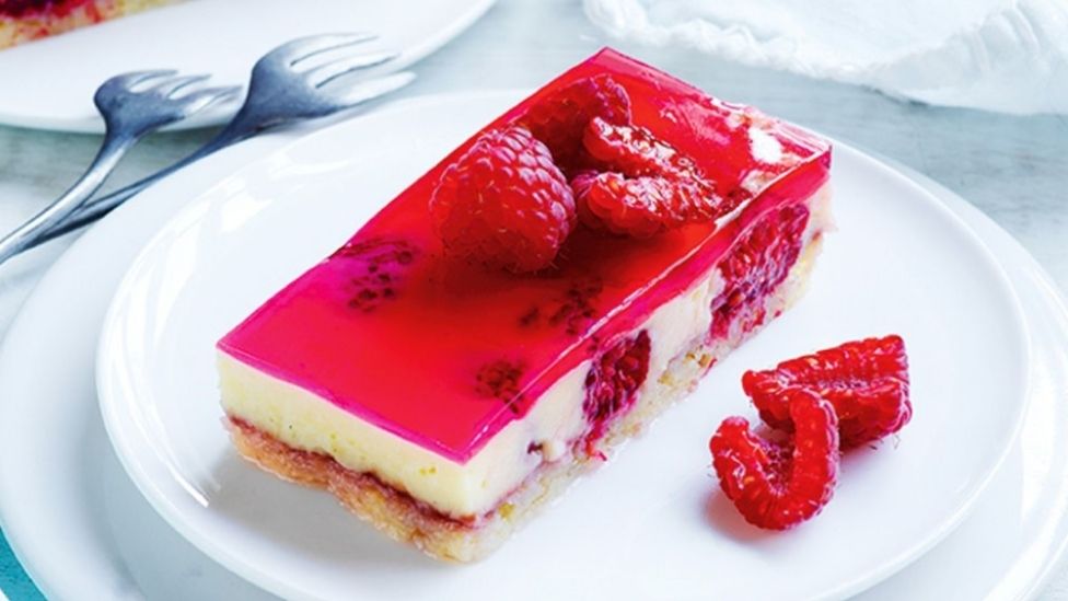 Raspberry trifle jelly slice decorated with sliced raspberries.