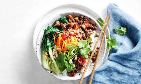 A bowl of mongolian styled beef on rice with veggies