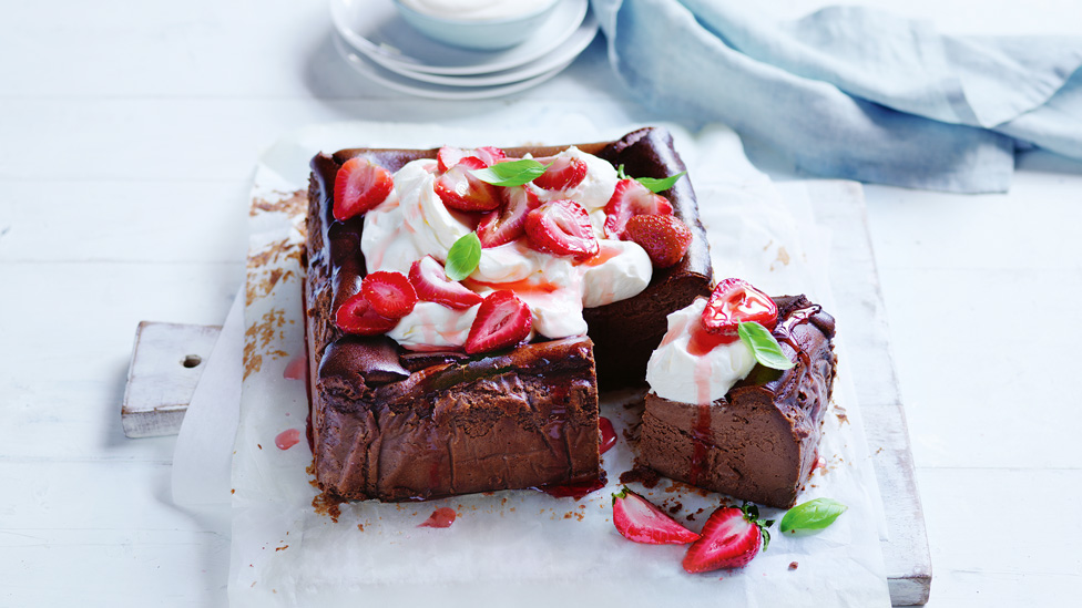 A basque chocolate cheesecake with cheese and roated strawberries on top