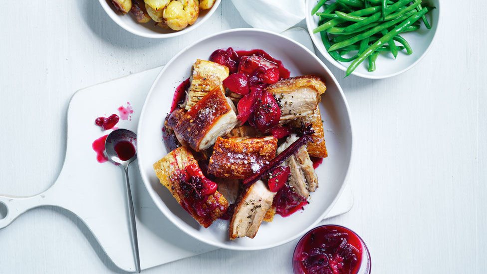 A plate of crispy pork belly with plum sauce on top