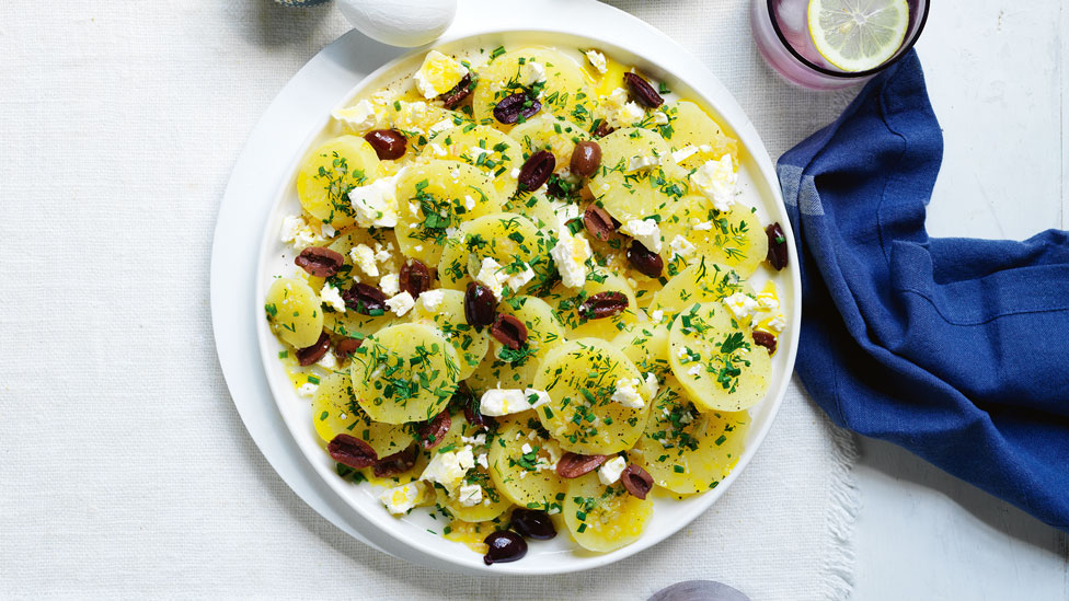 Peeled potatoes sprinkled with fetta and olives