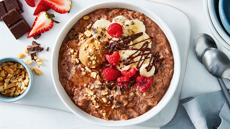 Choc peanut butter breakfast bowl topped with banana and raspberries