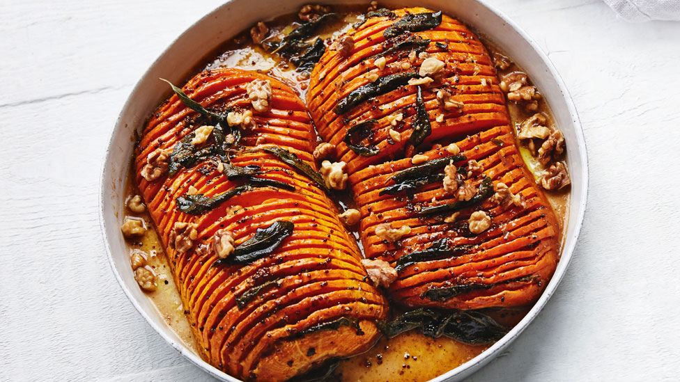 Hasselback pumpkin cut in half with sage and walnuts