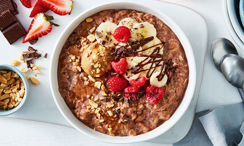 Choc peanut butter breakfast bowl topped with banana and raspberries
