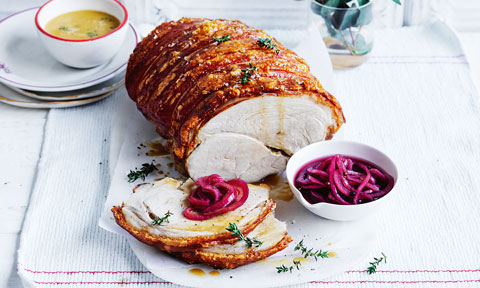 Thickly sliced crackling pork roast with pickled onions and cider jus