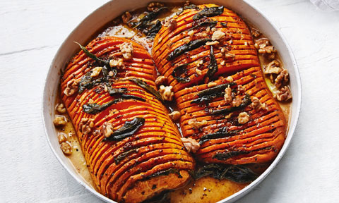 Hasselback pumpkin cut in half with sage and walnuts