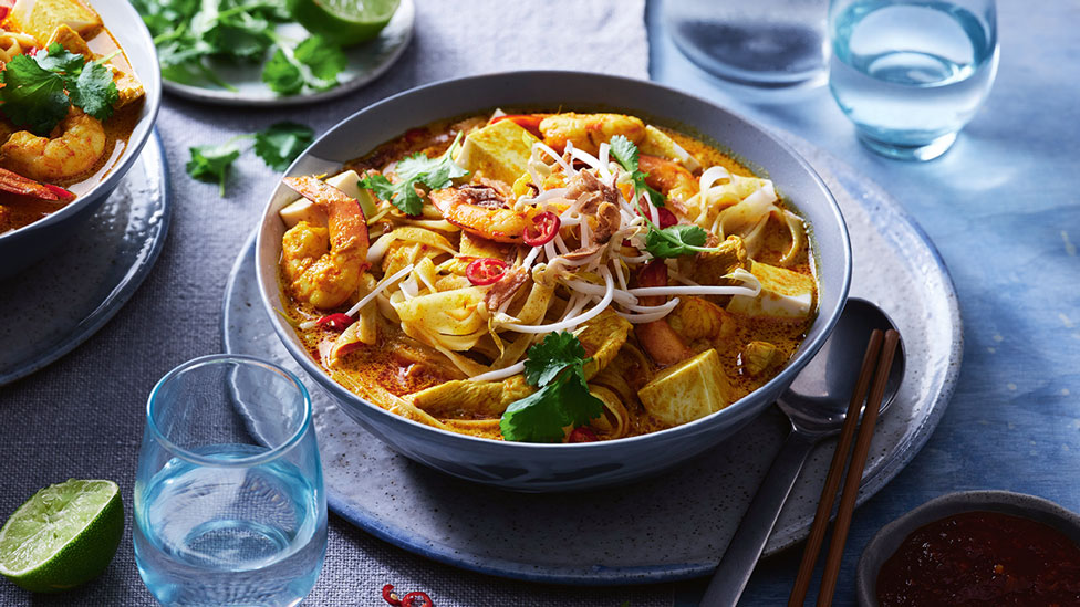 A bowl of laksa topped wtih fresh herbs