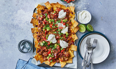 Chilli Con Carne Nachos, dressed with sour cream, red and green chilli, parsley and limes.