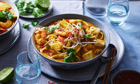 A bowl of laksa topped wtih fresh herbs