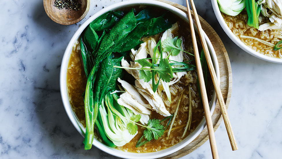 One serve of Hainanese chicken and rice soup, garnished with fresh coriander leaves.