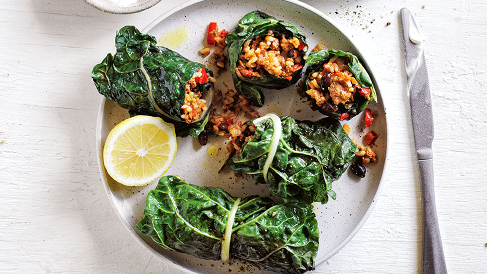 Five silverbeet & black bean burritos on a plate with lemon on the side.