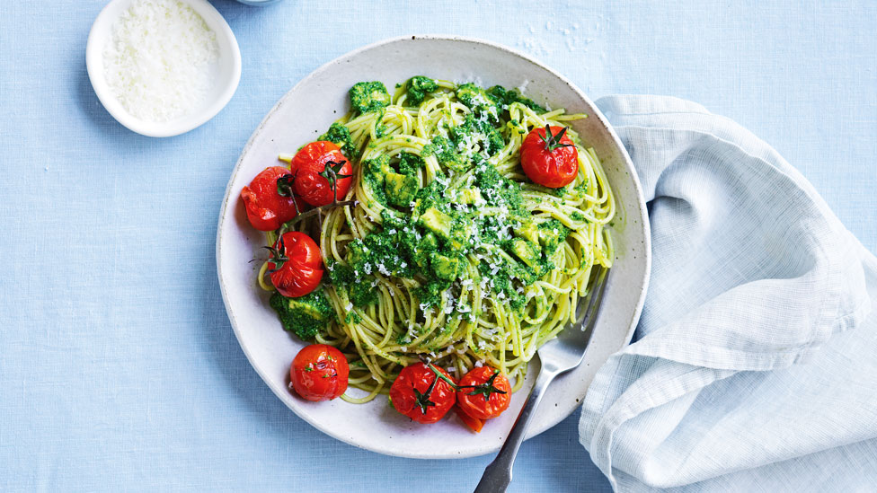 A bowl of avocado pesto pasta with cooked cherry tomatoes