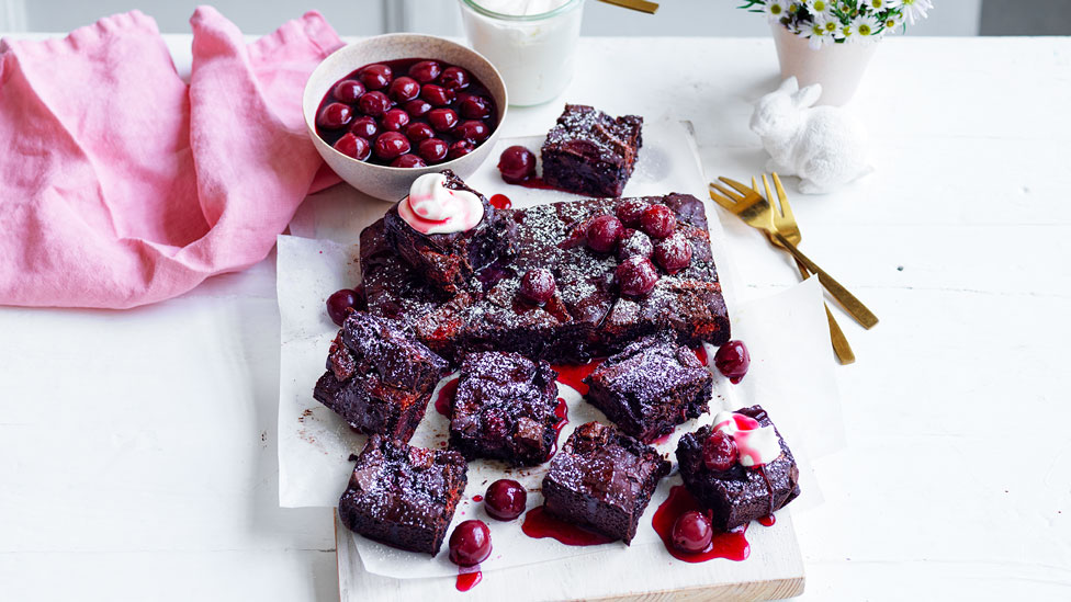 Black forrest brownies served with cherries next to a pink cloth