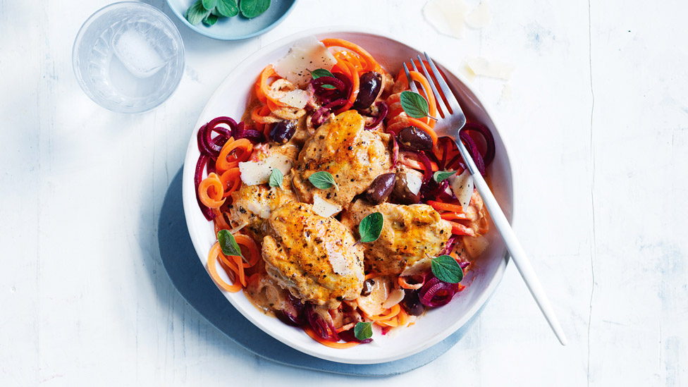 A bowl of veggie noodles topped with creamy pesto chicken