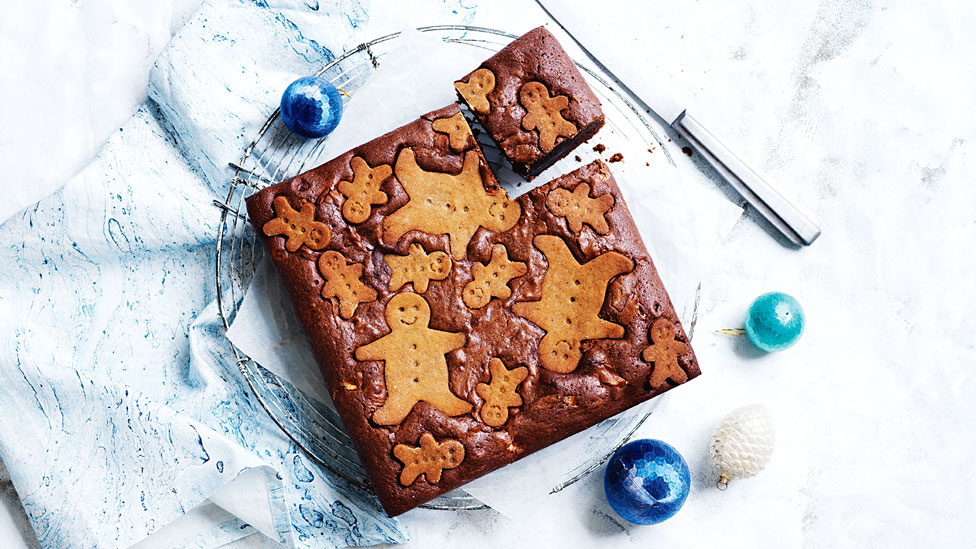 A gingerbread brownie on a blue cloth with christmas decorations