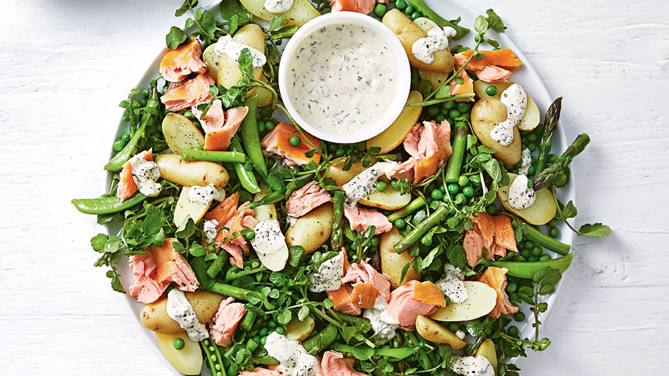 A hot smoked salmon and potato salad served with dressing in a bowl