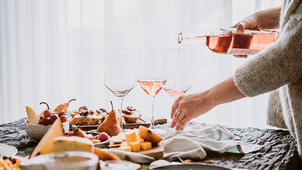 A lady pouring glasses of rose amongst a grazing board