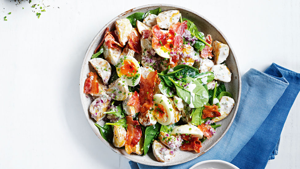 A warm potato salad in a bowl served with creamy dressing