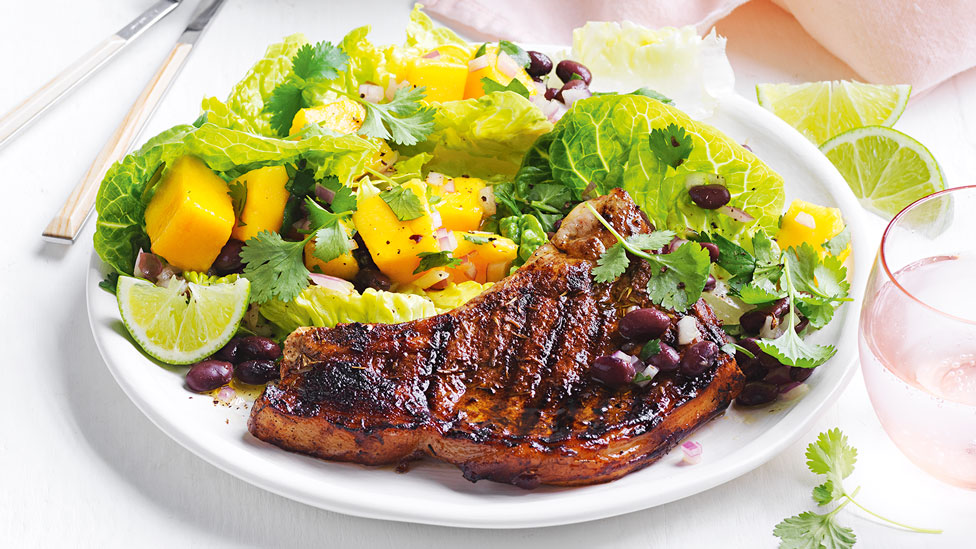 A pork chop with mango and black bean salad mixture