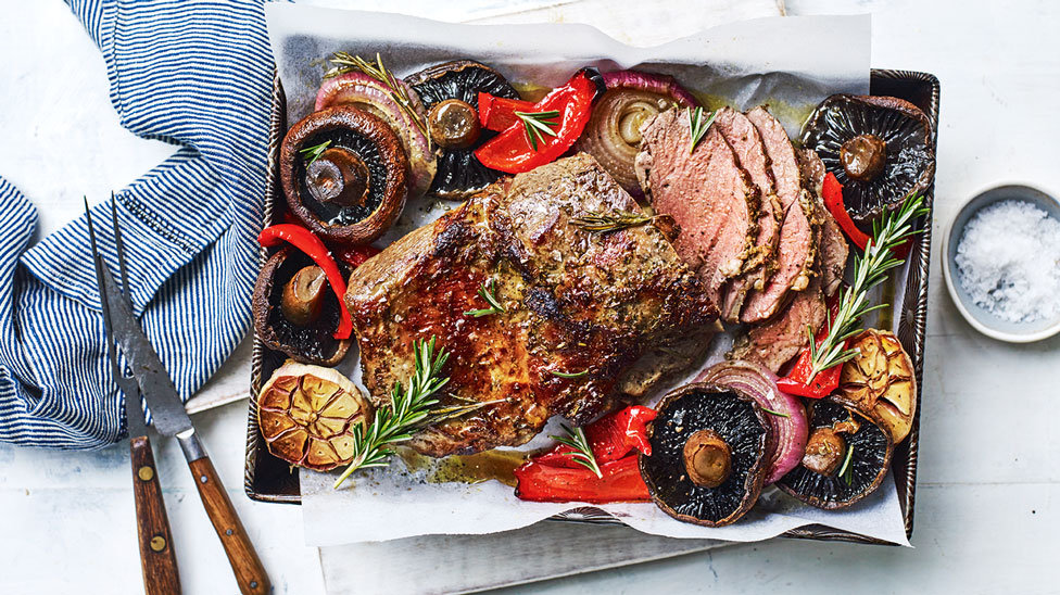 Lamb butterflied leg with rosemary and garlic on a dish.