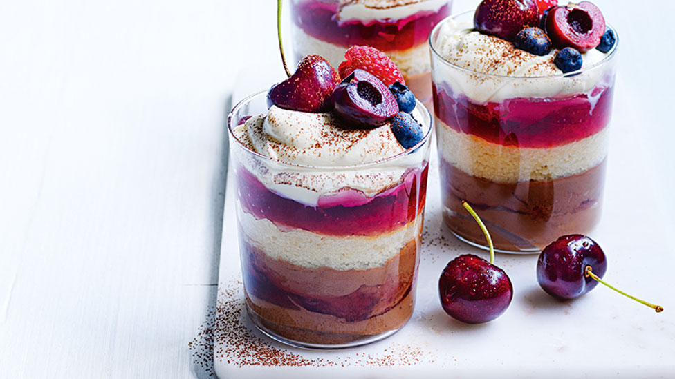 Two cups of chocolate and raspberry mini trifles with cheeries on top